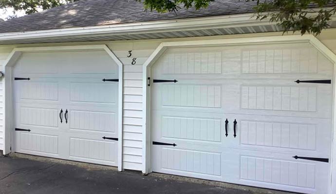 A residential garage featuring two white garage doors