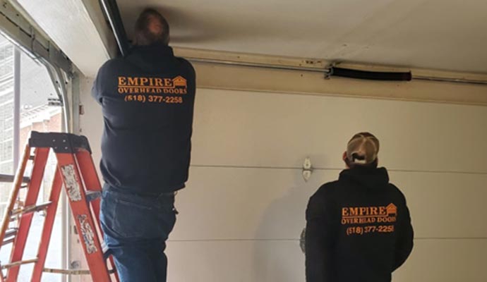 A professional team of Empire Overhead Doors is repairing the garage door