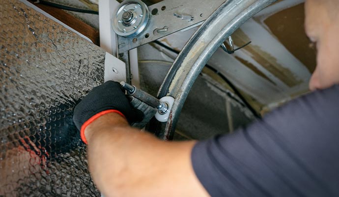 Technician adjusting garage door roller on track