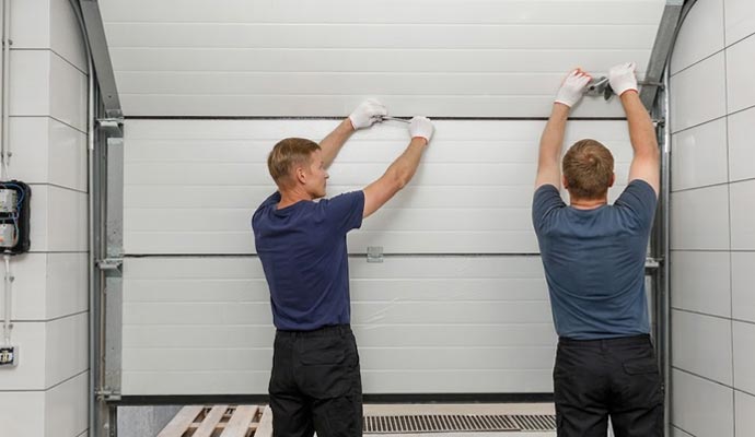 Technicians repairing sectional garage door
