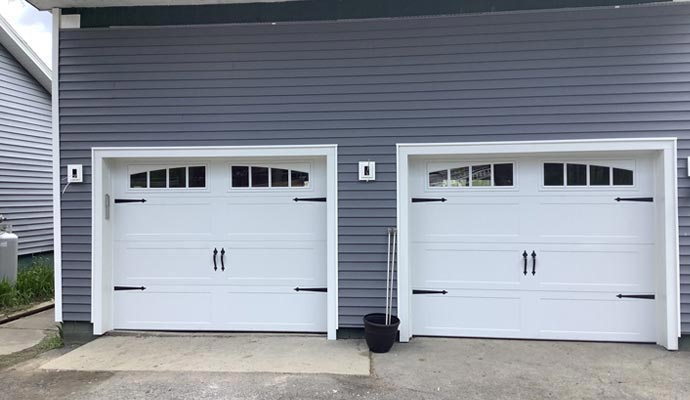 White carriage style garage doors on gray siding