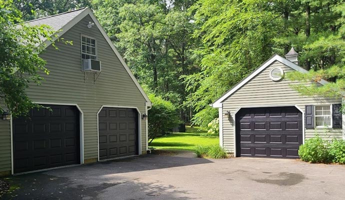 Matching black garage doors installed on a main house and detached workshop